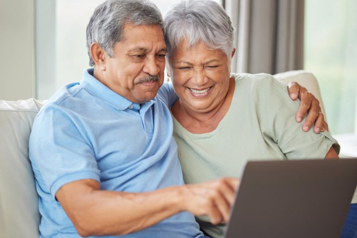 elderly-couple-laptop-video-call-social-media-internet-their-laptop-living-room-sofa-relax-senior-man-woman-watching-reading-news-email-funny-message-online-together-home